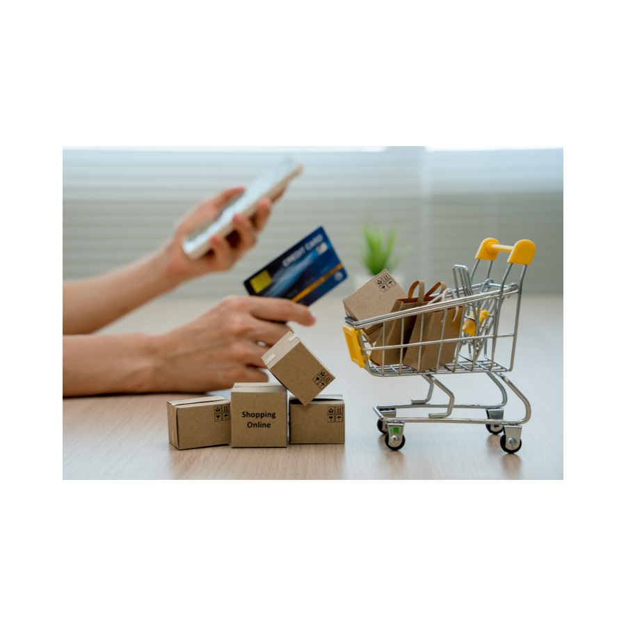 A customer completing an online purchase using a smartphone and credit card, with a miniature shopping cart filled with packages, perfectly encapsulating the swift and secure checkout process at SCR Sportswear.