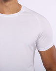 Close-up of a man wearing a plain white short-sleeve crew-neck athletic t-shirt, showing the fit on the chest and shoulder.