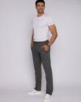 Confident tall male model wearing dark grey 34 inch long inseam athletic sweatpants with zipper pockets, lifestyle view