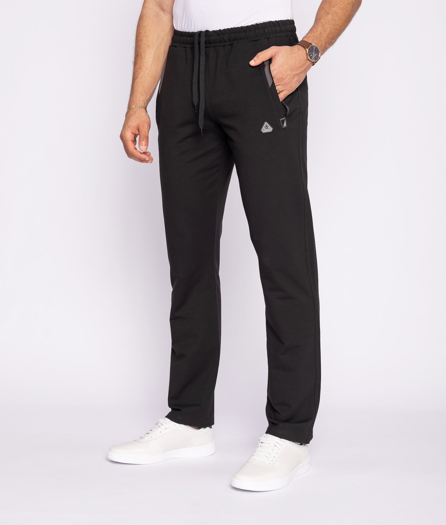 Person wearing black jogger pants with a white background