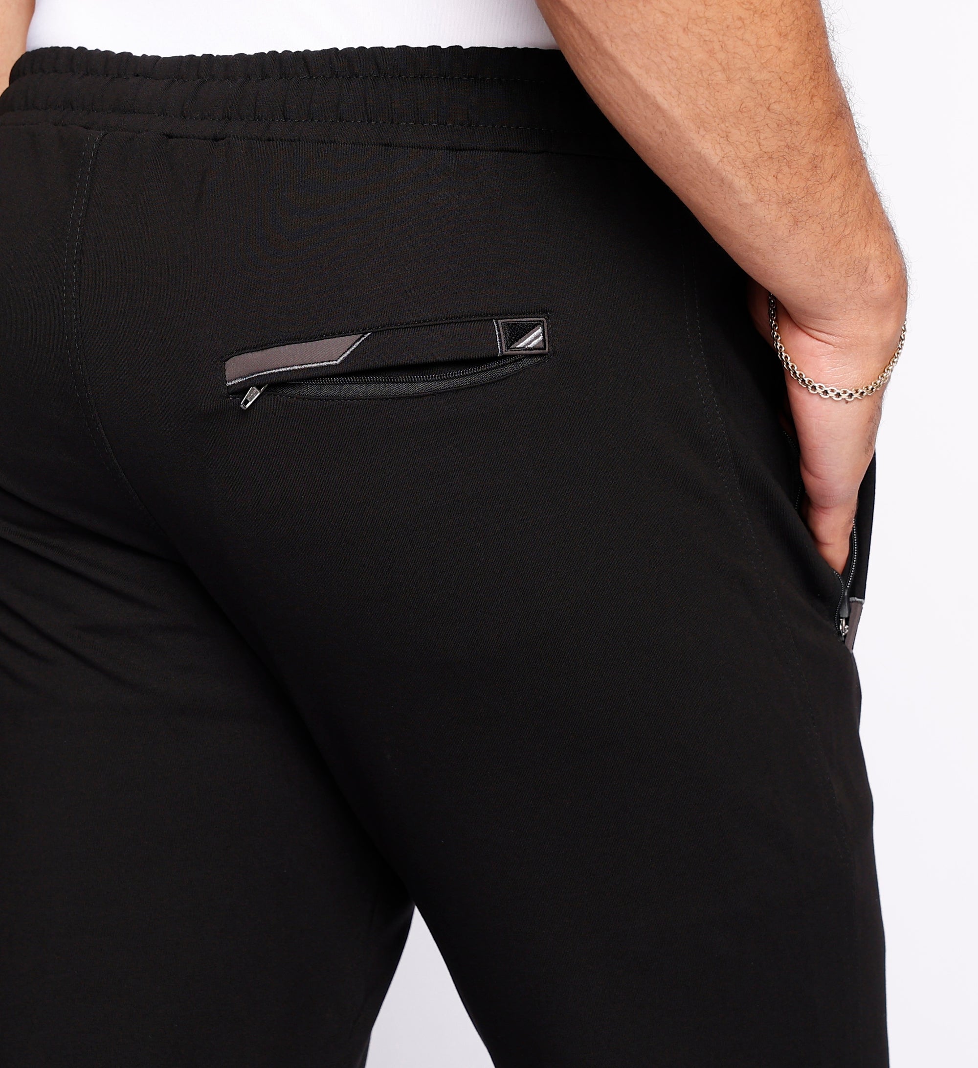 close-up of men’s black sweatpants highlighting rear zipper pocket, clean stitching lines, and stretch waistband with drawcord.