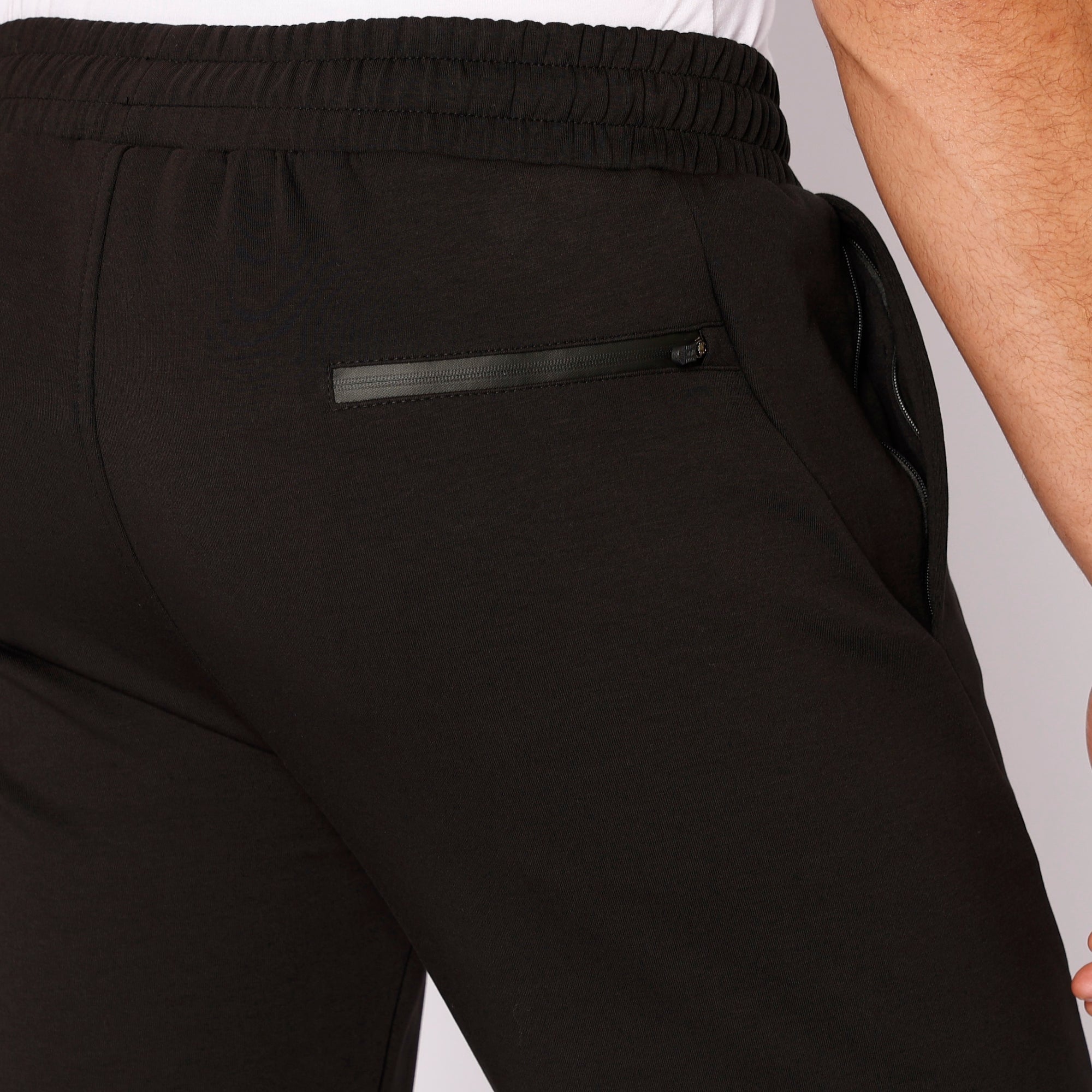 Detailed view of rear zipper pocket and elastic waistband on men's black relaxed-fit straight leg athletic pants - SCR Sportswear