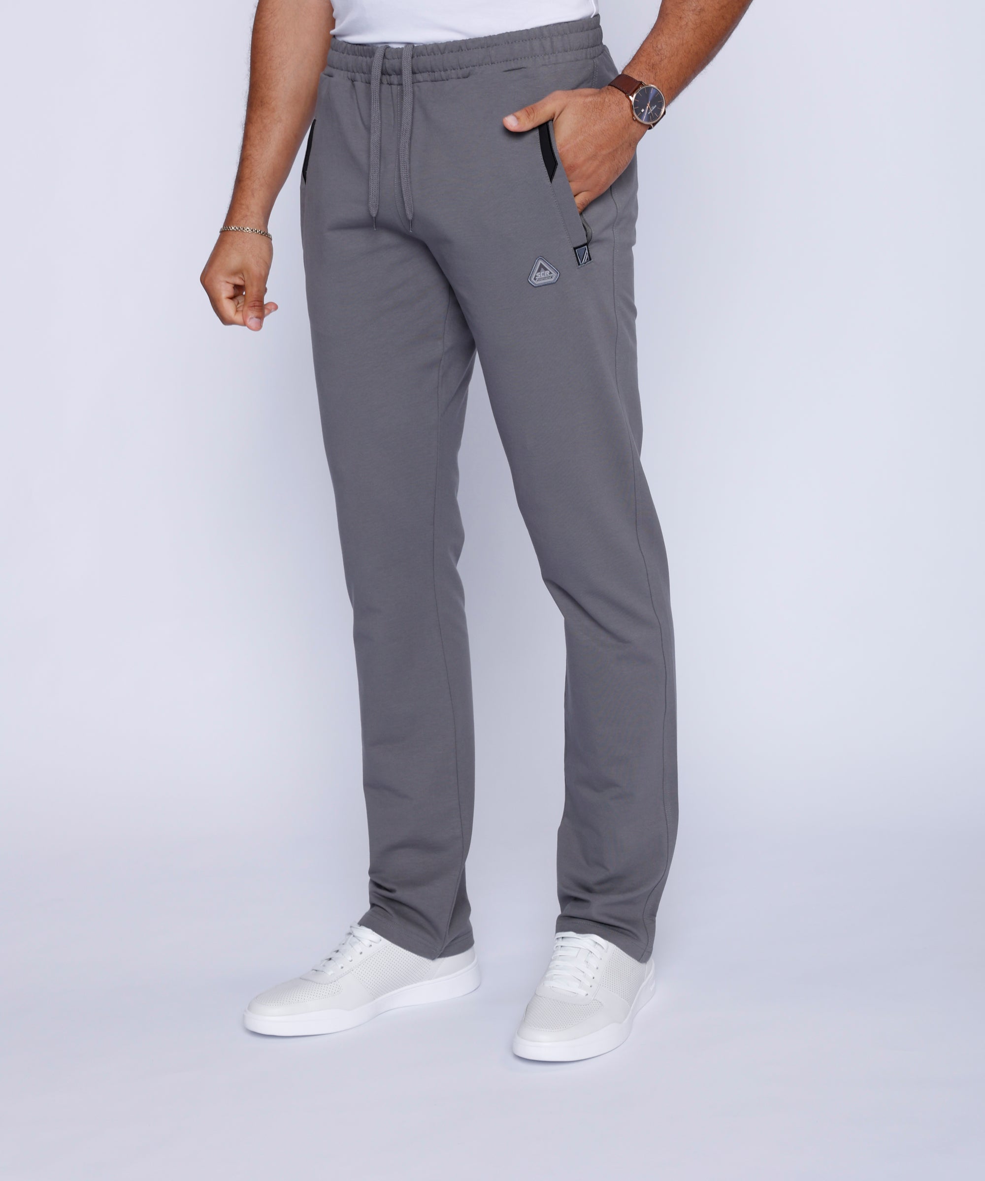 men’s light grey sweatpants with zipper pockets worn by male model, front full-body view with stretch waistband with drawcord.