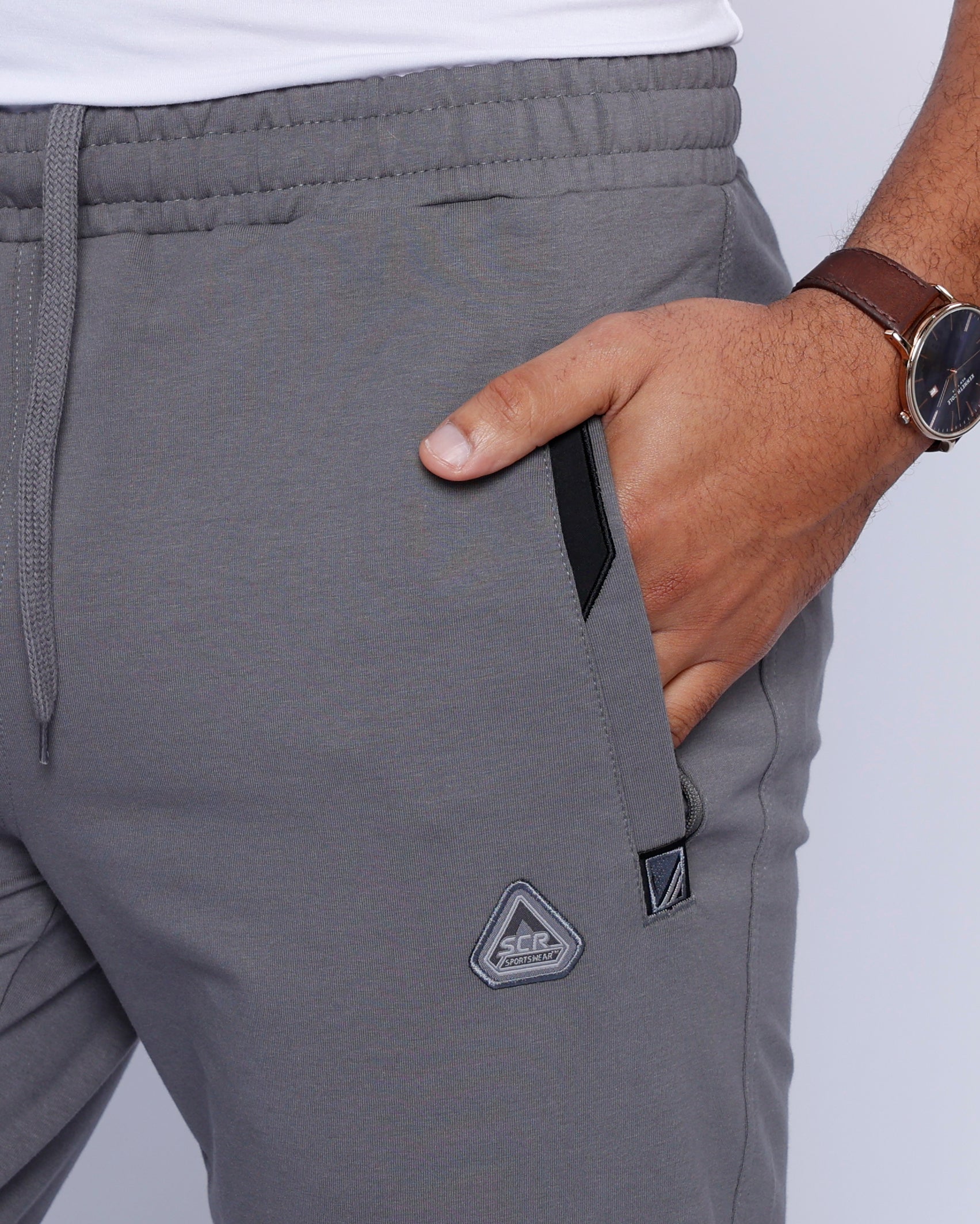 men’s light grey sweatpants worn by male model, close-up of front pocket and stretch waistband with drawcord