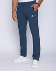 Front view of men’s steel blue sweatpants with straight leg cut, zippered pockets, and stretch waistband with drawcord, worn by male model in white t-shirt and white shoes.
