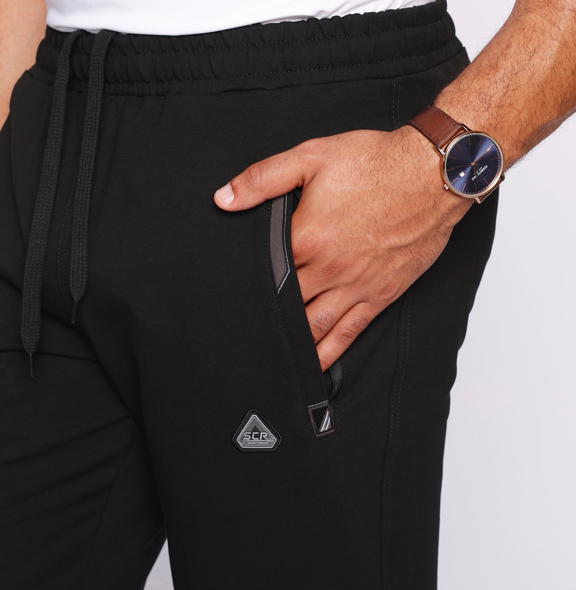 close-up of men’s black sweatpants showing front zipper pocket detail, stretch waistband with drawcord, and soft premium fabric texture