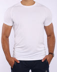 A man wearing a white short-sleeve athletic t-shirt and dark navy pants, standing against a light gray background.