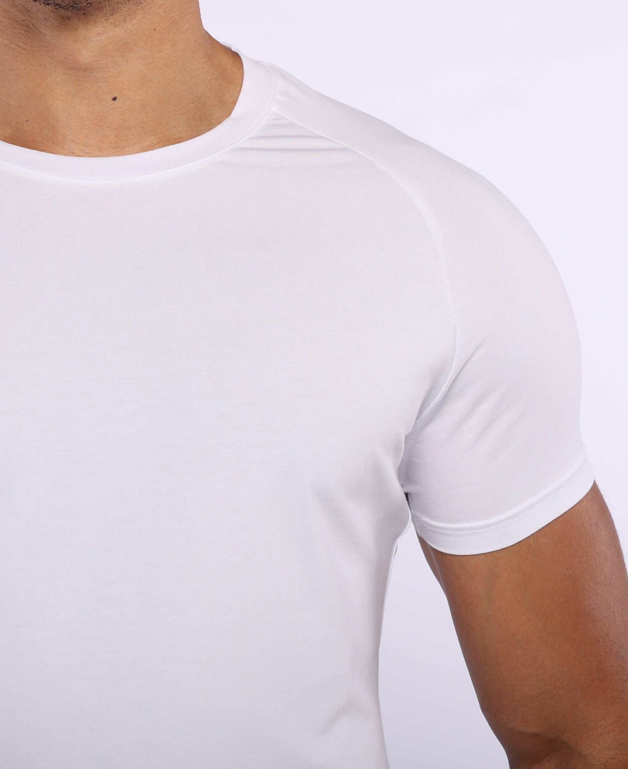 Close-up of a man wearing a plain white short-sleeve crew-neck athletic t-shirt, showing the fit on the chest and shoulder.