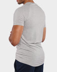 A man wearing a light gray heathered short-sleeve t-shirt, shown from a rear three-quarter angle against a plain light gray background.