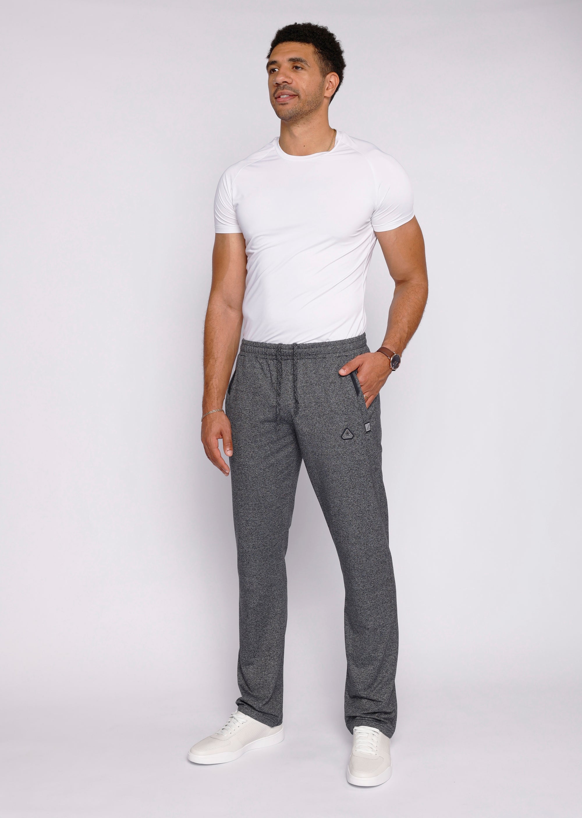 Confident tall male model wearing heather grey athletic sweatpants with long inseam  zipper pockets, lifestyle view